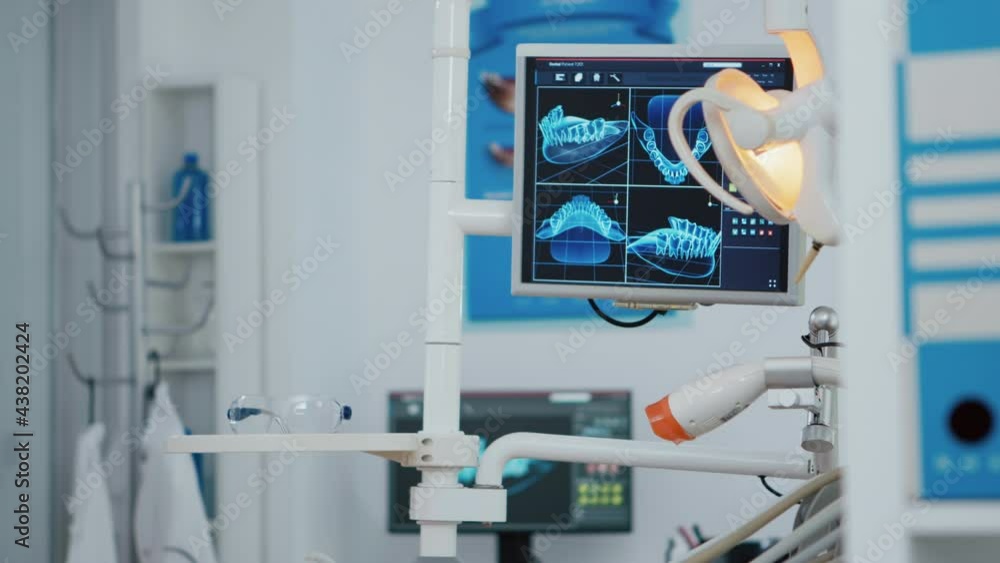 Close up of medical orthodontist display with x ray images on it. Empty professional hospital stomatology chair with nobody in it. Close up revealing shot. Modern dentist equipment Close up of medical orthodontist display with x ray images on it. Empty professional hospital stomatology chair with nobody in it. Close up revealing shot. Modern dentist equipment