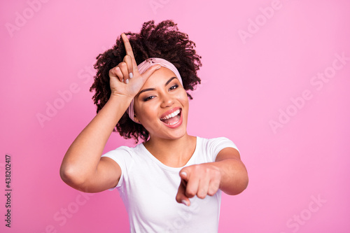 Portrait of brunette optimistic lady show loser sign wear white t-shirt hairband isolated on pastel pink background photo