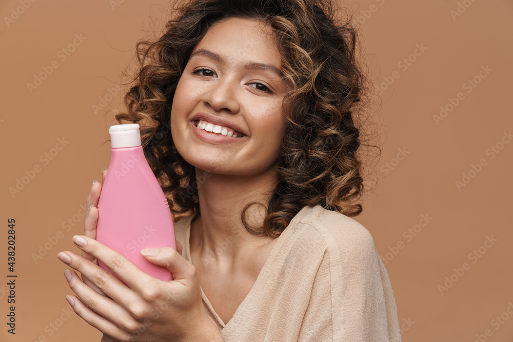Young curly hispanic woman smiling while showing beauty product Young curly hispanic woman smiling while showing beauty product