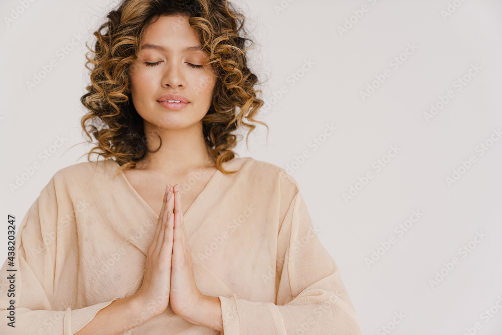 Young hispanic woman holding her palms together while posing on camera Young hispanic woman holding her palms together while posing on camera
