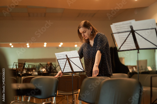 Focused woman reading sheet music in concert hall photo