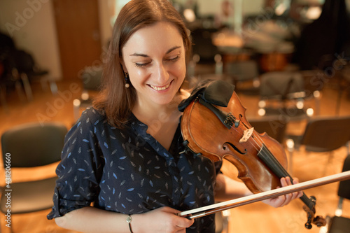 Happy female violinist performing classical music in hall photo