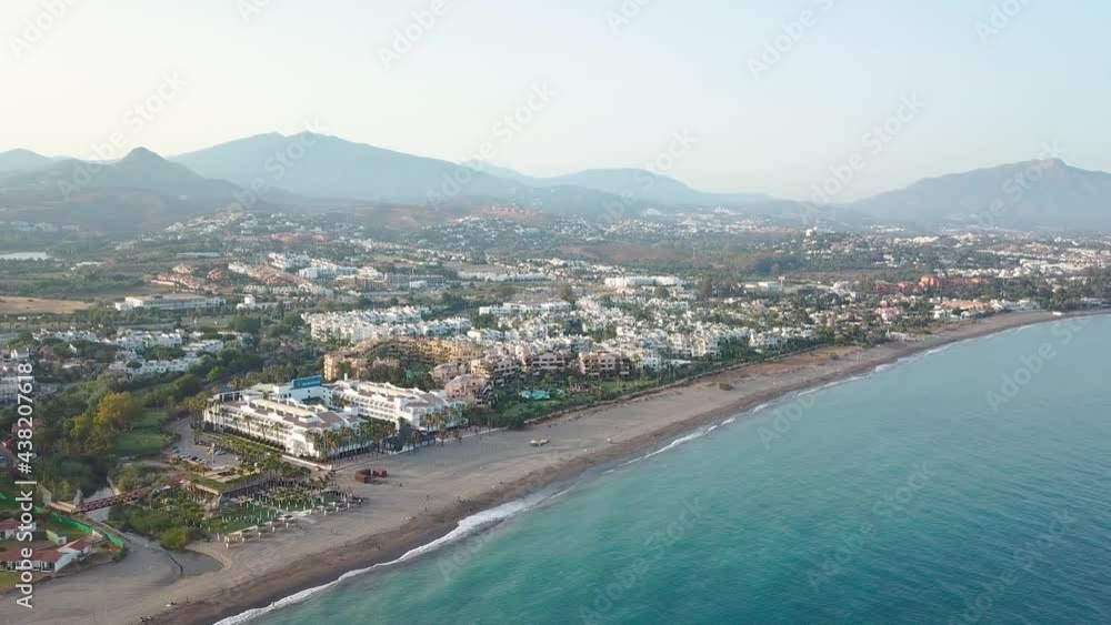 Beautiful sunset over luxury urbanisation, real estate, Costa del Sol, Marbella. In background Sierra Blanca mountains. Drone going backward creating a beautiful panoramic perspective of the village. Beautiful sunset over luxury urbanisation, real estate, Costa del Sol, Marbella. In background Sierra Blanca mountains. Drone going backward creating a beautiful panoramic perspective of the village.