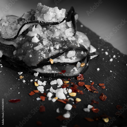 Composizione di melanzane , polpa di pomodoro e formaggio su di un piatto di ardesia in bianco e nero con alcuni dettagli del piatto a colori. photo