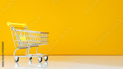 empty shopping cart. Minimum concept. Yellow and white background. place for a note