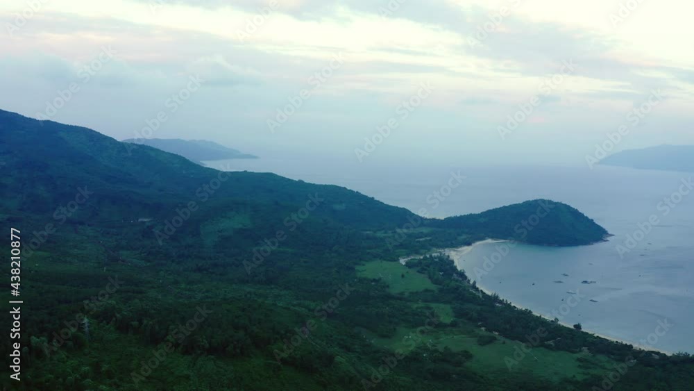 Aerial Shot Of Beautiful Green Landscape By Sea Against Sky, Drone Flying Backward Over Mountains - Hue, Vietnam Aerial Shot Of Beautiful Green Landscape By Sea Against Sky, Drone Flying Backward Over Mountains - Hue, Vietnam