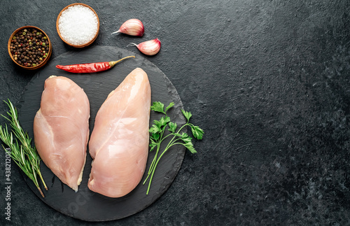 Raw chicken breasts with spices on a stone background with copy space for your text