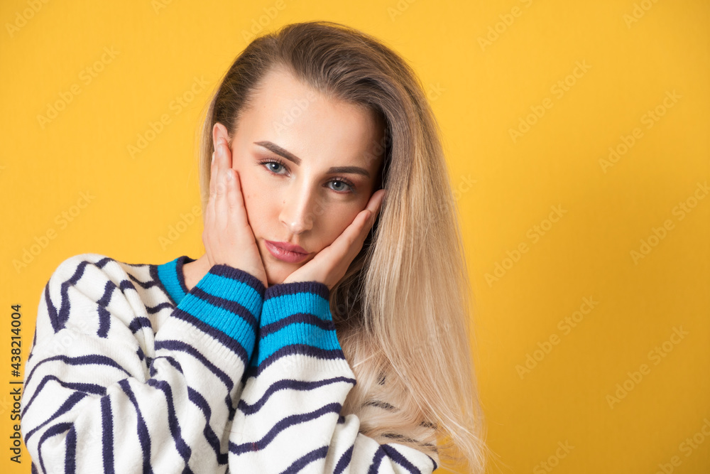 Head shot of young gorgeous woman with hands keeping on cheek, isolated on yellow background. Close up face of beautiful girl Head shot of young gorgeous woman with hands keeping on cheek, isolated on yellow background. Close up face of beautiful girl