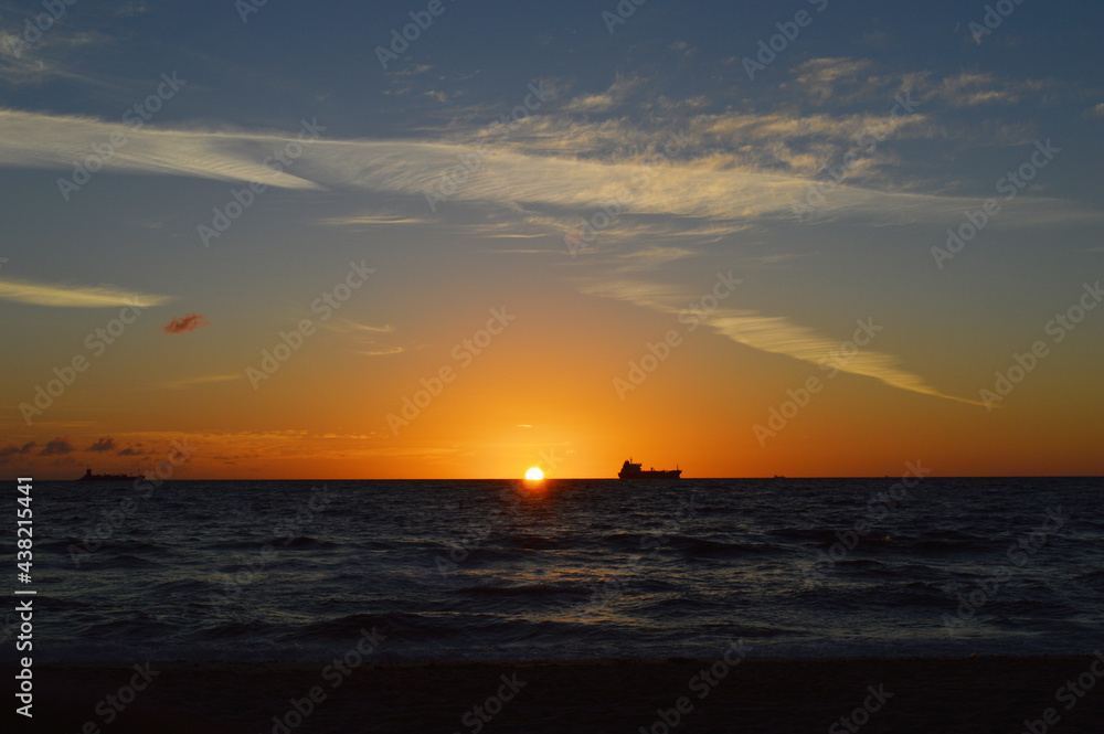 Beautiful Sunrise over the ocean line on Fort Lauderdale Beach with fishing boat far away