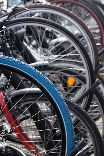 Detail of the wheels of parked bicycles in Maastricht, Netherlands. Focus on the blue bicycle tire in front. Vertical photo with selective focus. Dutch bicycle parking. City biking