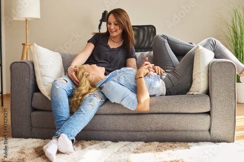 Young female gay couple sitting on a sofa and smiling