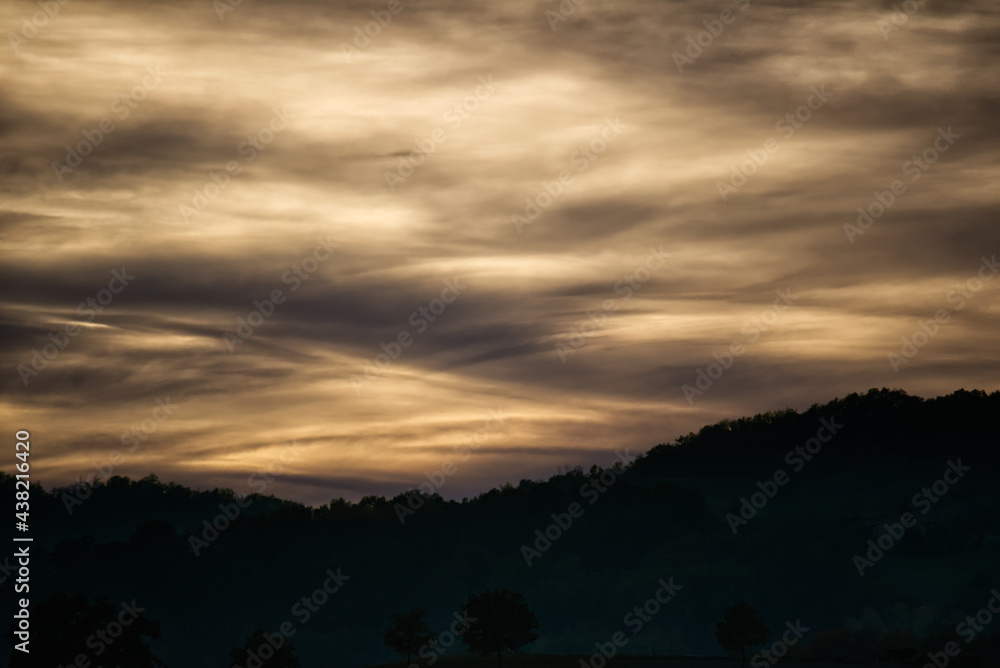 Trama delle nuvole al tramonto tra le colline.