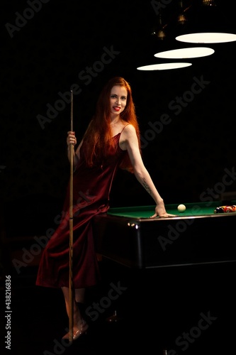 The nice young girl with cue at a billiard table