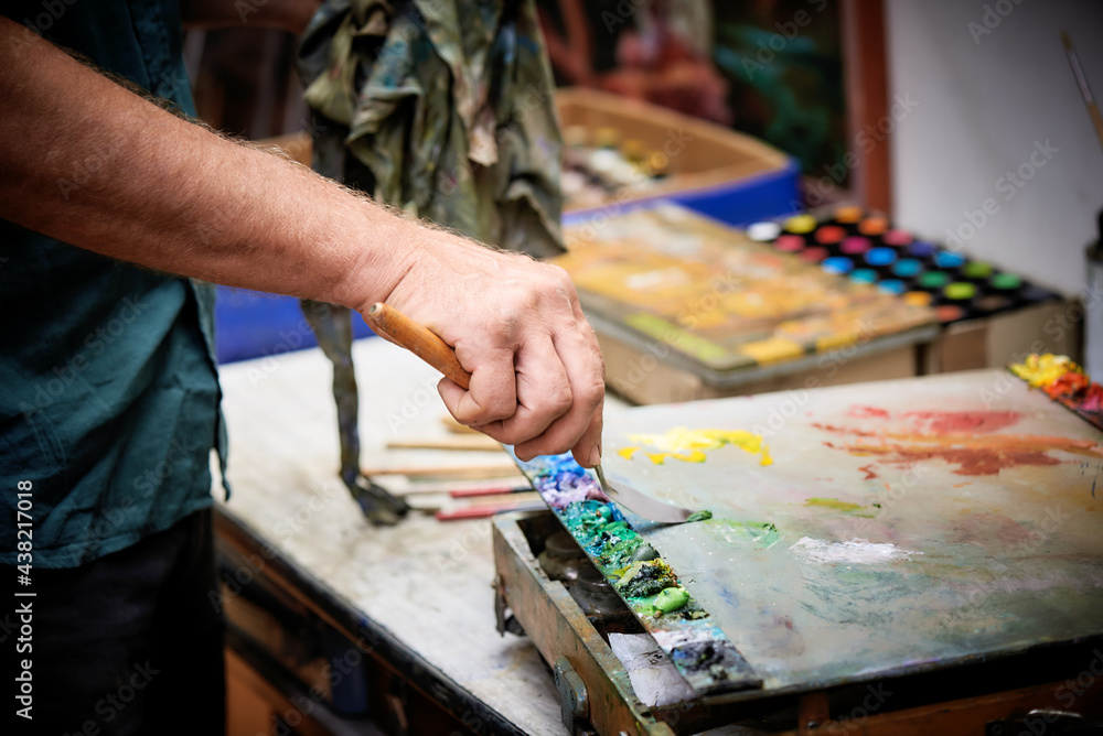 Artist working on big painting with a palette knife and paintbrush in studio Artist working on big painting with a palette knife and paintbrush in studio