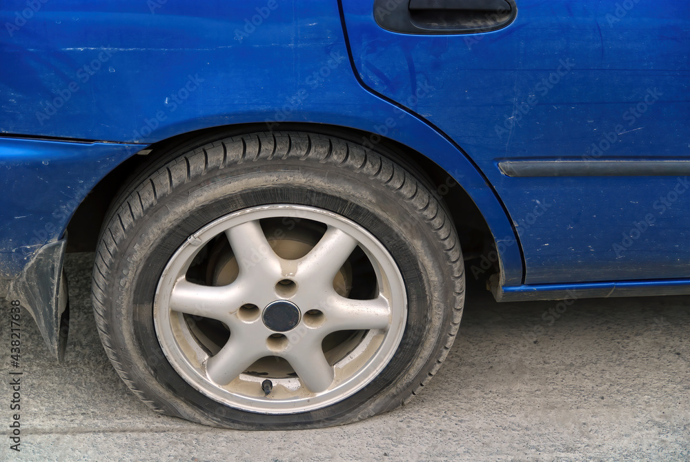 Flat tire. wheel of the car after an accident. Broken rubber. Close up of car vehicle automobile punctured by nail or sharp rock.