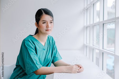 A beautiful nurse sits in a chair with a gloomy and anxious expression, nursing the concept with trust and care.