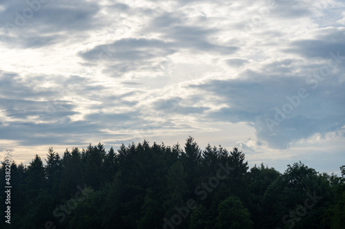 Wolken über einem Hügel mit Wald