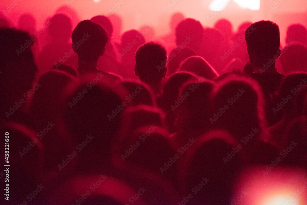 Silhouette of concert crowd at music festival in red stage lights