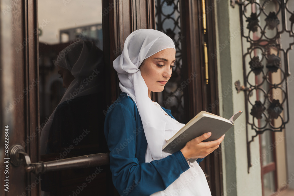 Φωτογραφία Portrait of young muslim woman wearing hijab reading book outdoors