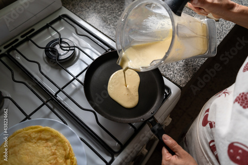 Woman cook preparing pancakes in a frying pan