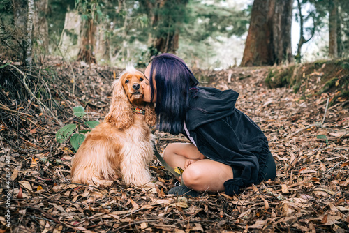 Woman giving her dog a kiss amid the dry leaves of a beautiful forest photo