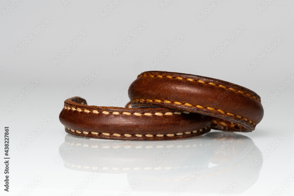 Handmade brown leather cuff bracelet for men or women isolated on white background with reflection. Copy space for text message. Horizontal shot. Handmade brown leather cuff bracelet for men or women isolated on white background with reflection. Copy space for text message. Horizontal shot.