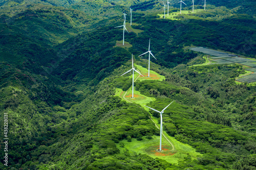 Aerial photo of white windmills in a line on green land leading off into the horizon.