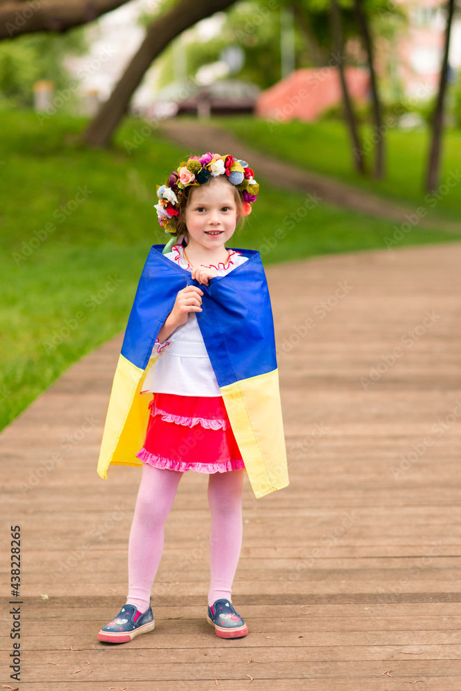 Girl with the flag of Ukraine. She is dressed in an embroidered shirt and a wreath on her head - Ukrainian national dress. August 24 - Independence Day of Ukraine.