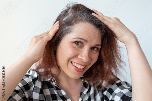 Young woman shows her gray hair roots. Early aging concept.