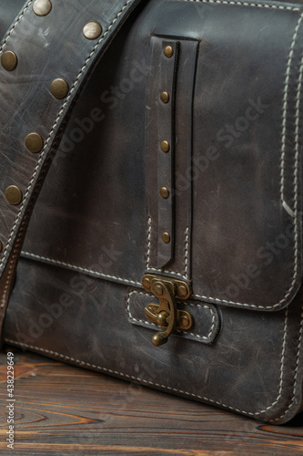 Close-up of the belt buckle of a retro style dark leather messenger bag.