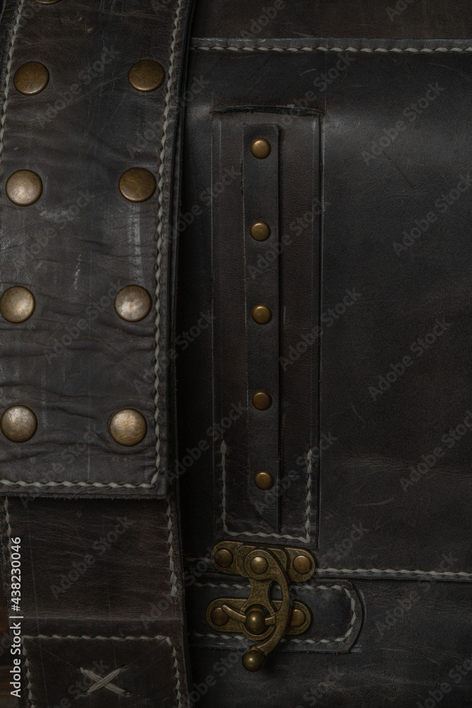 Close-up of the belt buckle of a retro style dark leather messenger bag.