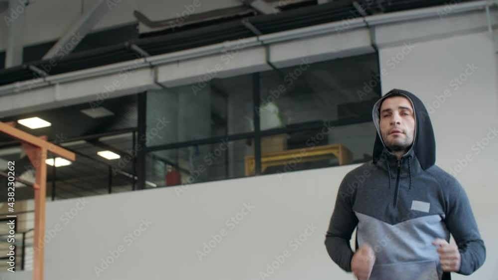 Sportsman in hoodie training run while cardio exercise inside fitness club. Athlete man jogging on treadmill inside gym. Sportsman in hoodie training run while cardio exercise inside fitness club. Athlete man jogging on treadmill inside gym.