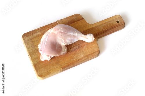 Piece of raw chicken - thigh - lies on a cutting board, isolated on a white background