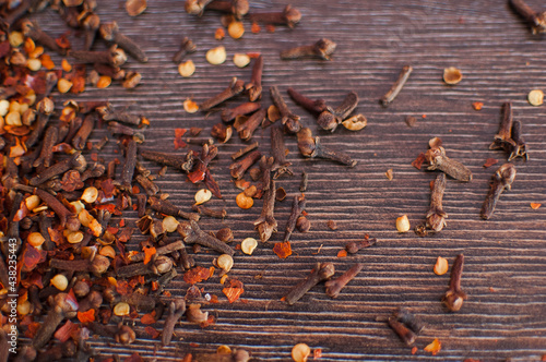 Dry cloves spice and red hot chili pepper flakes on a wooden background. Healthy, spicy ingredient for cooking