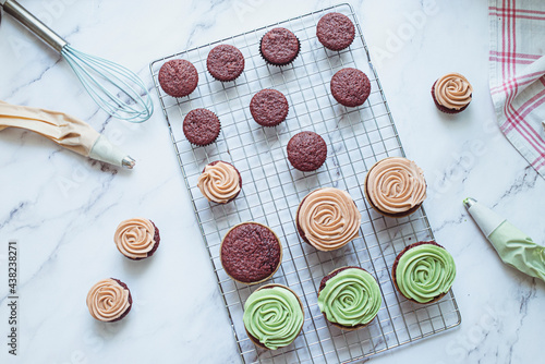 Overhead view of chocolate cupcakes with mint and coffee buttercream icing on a cooling rack photo