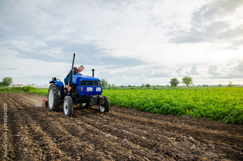 Farmer with tractor working in the field. Milling soil, crushing and loosening ground before cutting rows. Preparatory earthworks before planting a new crop. Land cultivation. Farming, agriculture. Farmer with tractor working in the field. Milling soil, crushing and loosening ground before cutting rows. Preparatory earthworks before planting a new crop. Land cultivation. Farming, agriculture.