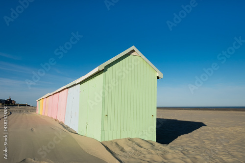 Multicolored beach huts lined up on the deserted beach of Berck in France © Erik_AJV