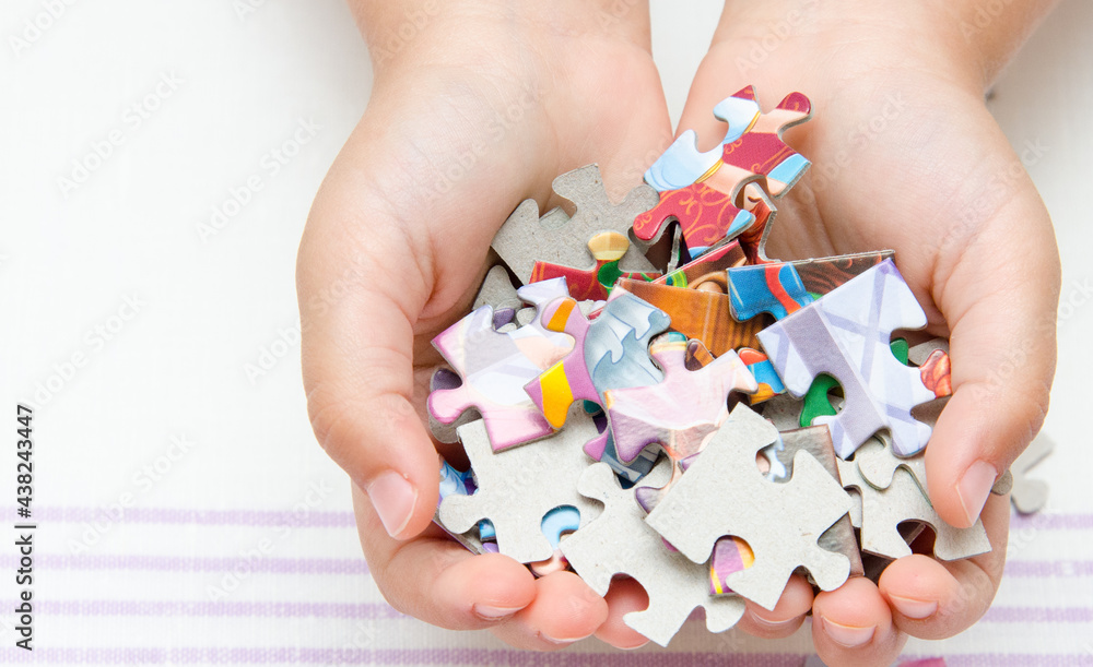 The child holds the details of a colored puzzle. Pieces of the puzzle in the hands of a child. The child holds the details of a colored puzzle. Pieces of the puzzle in the hands of a child.