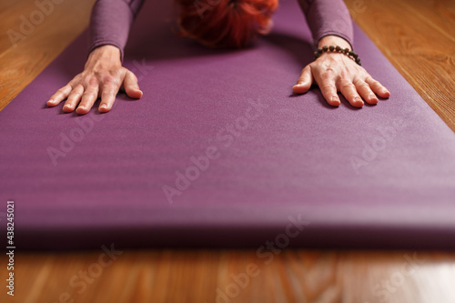 The girl does yoga in the asana stand on a lilac mat.