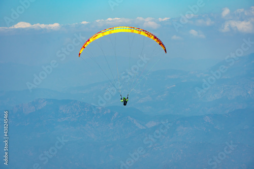 Paraglider soaring on paragliding in the sky in mountain. Extreme sport in mountains