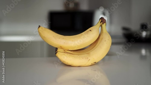 Zoom in footage of a bunch of yellow bananas on the white kitchen countertop 