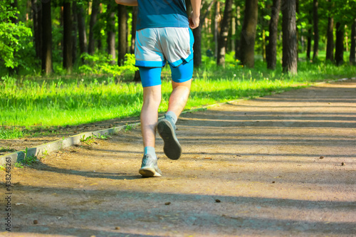 A sporty fitness man jogging in a park on a sunny spring summer day. Lifestyle.