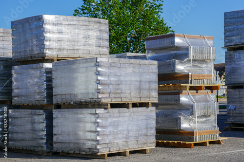 A pile of new paving slabs on a wooden pallet wrapped in transparent plastic wrap