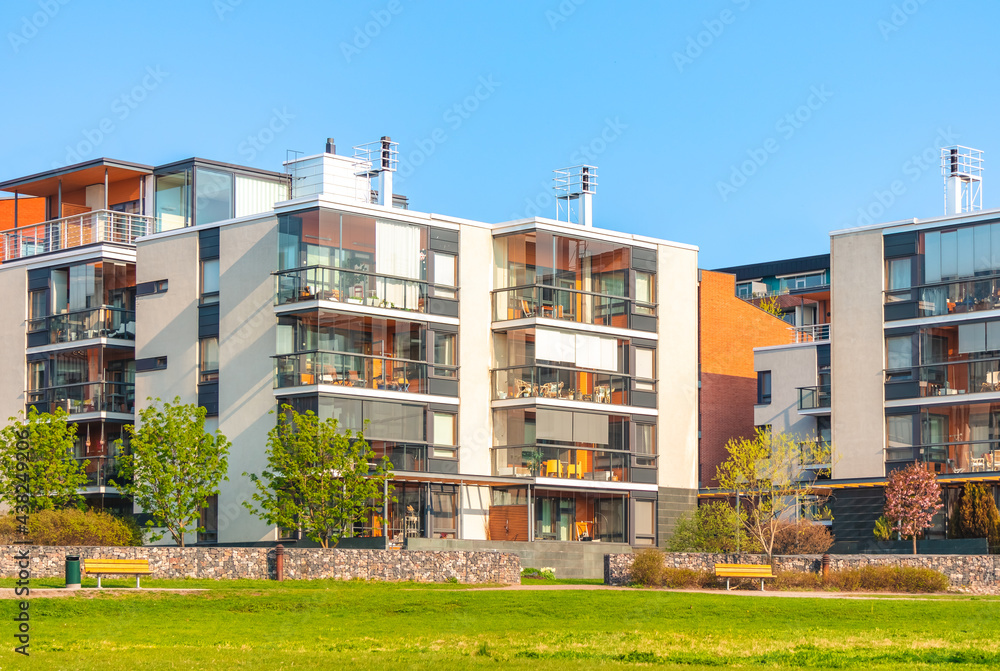 European residential complex of apartment buildings. Outdoor facilities. New modern block of flats with cozy courtyard and green area. Eco-friendly living in city. Scandinavian architecture. Exterior.