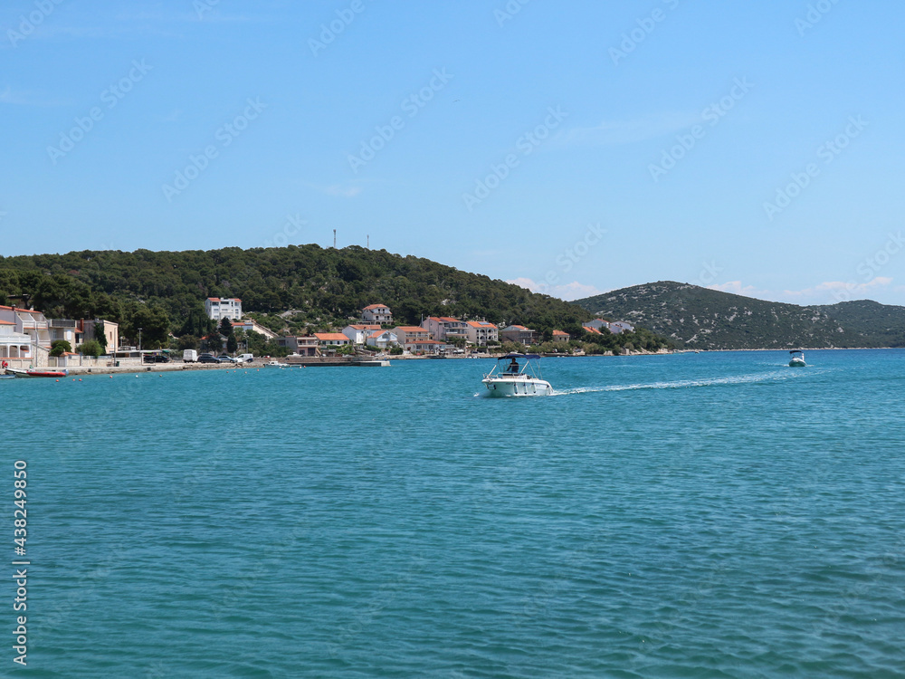 Boats approaching small town of Tisno on the Murter island, Croatia, famous for summer music festivals and wonderful turquoise sea on the Adriatic coast