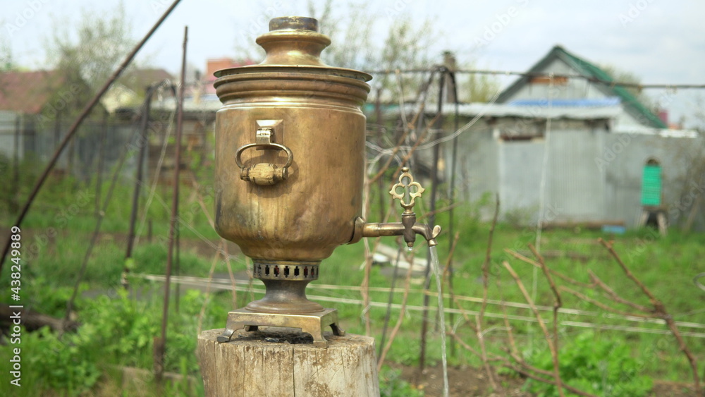 Boiling water is pouring from an old brass samovar. Making tea in a samovar Boiling water is pouring from an old brass samovar. Making tea in a samovar