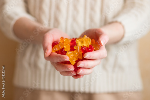 Close-up image of a woman holding multi-colored gummy bears.