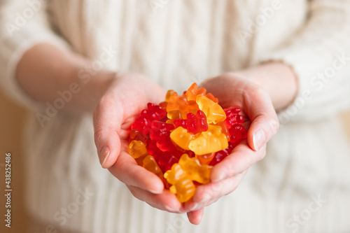 Close-up image of a woman holding multi-colored gummy bears.