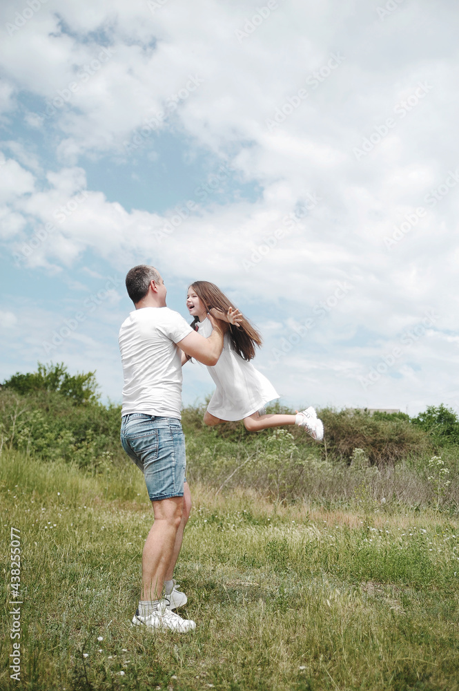Dad throws his daughter into the sky. Happy family concept. Dad and daughter have fun in the field . 
