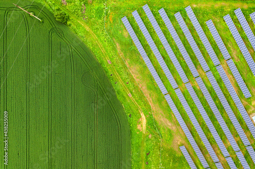 Aerial view of solar power plant on green field. Electric panels for producing clean ecologic energy.